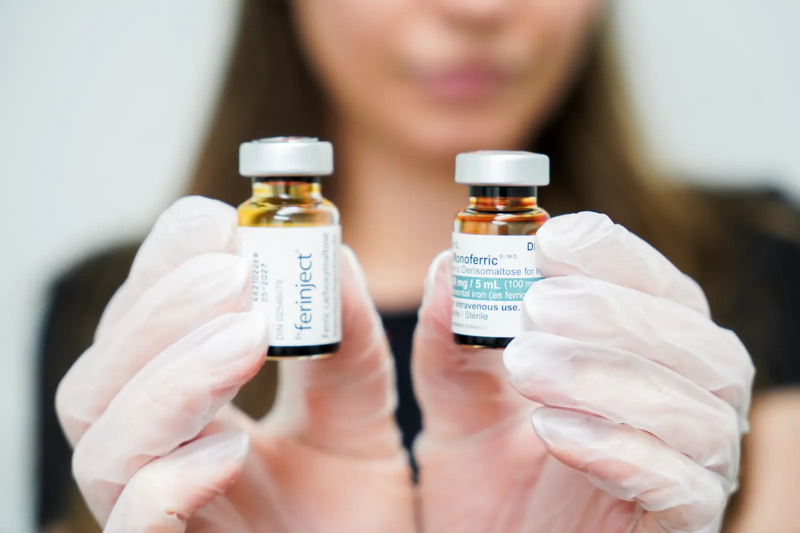 Care& clinician holding intravenous iron vials used for iron infusion therapy